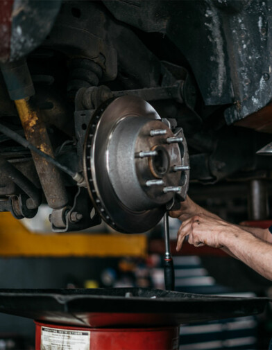 The hands of a car mechanic working around a wheel axle