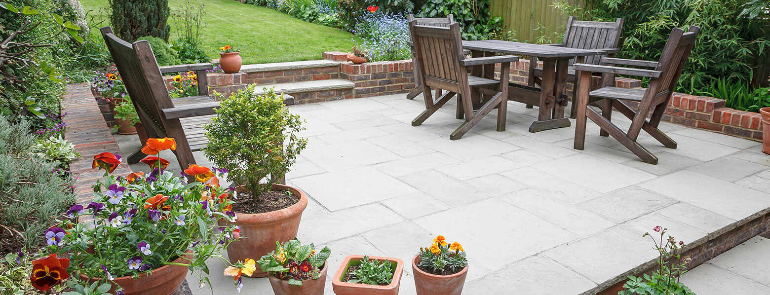 20x20 foot stamped concrete patio with furniture and lush plants around it