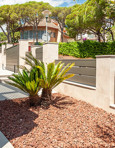 View of sunlit yard with tipple red stone around the plants