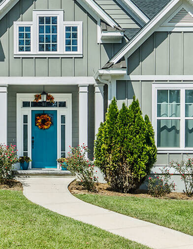 A smooth, pale sidewalk curves elegantly up to the blue front door of a modern home